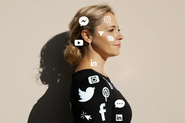 Žena stojí ve světle, obklopená ikonami sociálních sítí na černém oblečení. Symbol propojení, zahlcení i hledání rovnováhy mezi online a skutečným světem.